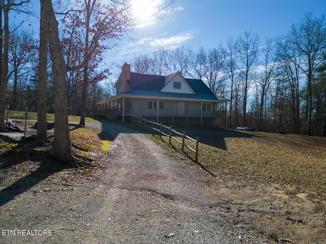 farmhouse inspired home featuring driveway, a porch, and a chimney