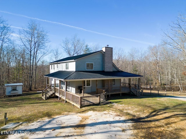 view of front facade with a front yard, metal roof, an outdoor structure, and a chimney