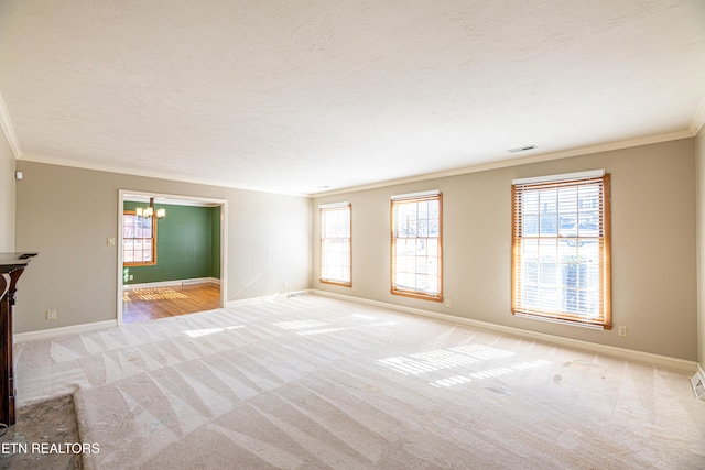 carpeted spare room with ornamental molding, a textured ceiling, and a chandelier