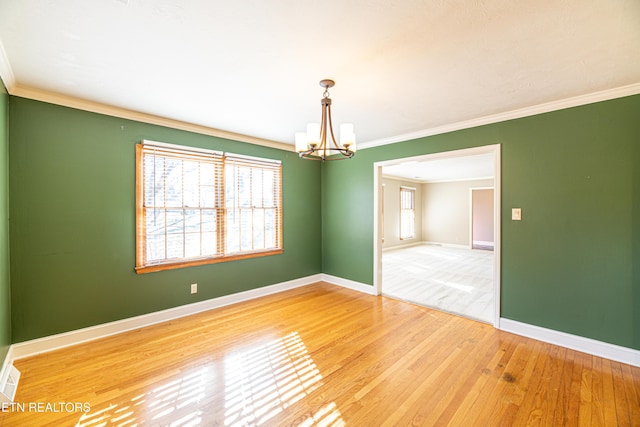 unfurnished room featuring an inviting chandelier, ornamental molding, and wood-type flooring