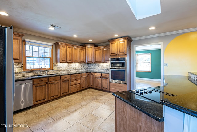 kitchen with sink, a skylight, stainless steel appliances, and a healthy amount of sunlight