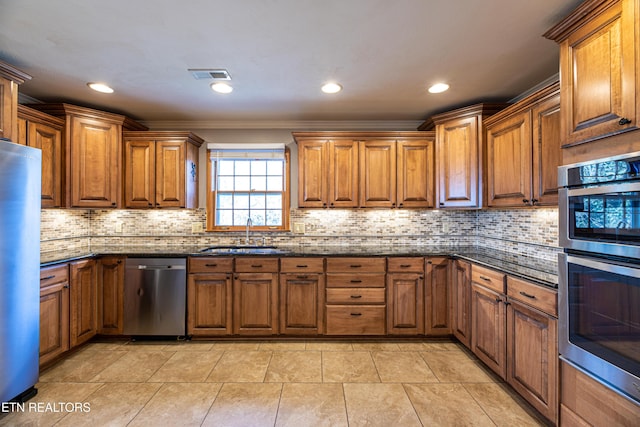 kitchen with sink, dark stone countertops, ornamental molding, stainless steel appliances, and backsplash