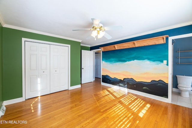 bedroom with crown molding, ensuite bath, ceiling fan, hardwood / wood-style floors, and a closet