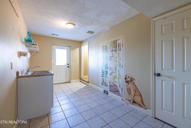 interior space featuring sink, a textured ceiling, and light tile patterned floors