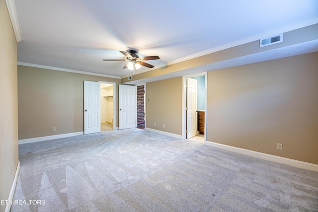 unfurnished bedroom featuring crown molding, light colored carpet, ceiling fan, and ensuite bathroom