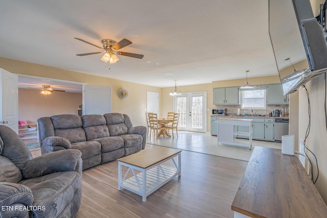 living room featuring french doors, ceiling fan, sink, and light hardwood / wood-style flooring