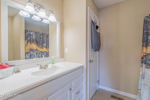 bathroom with an inviting chandelier, tile patterned floors, and vanity