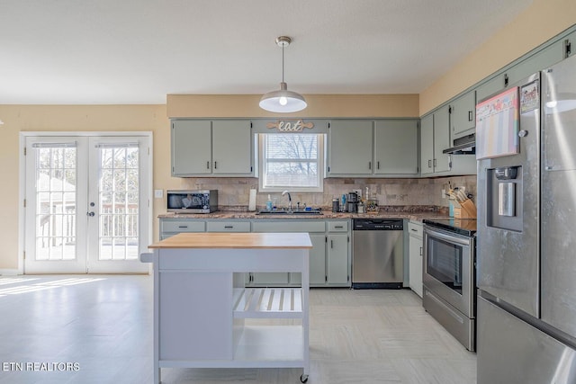 kitchen with sink, backsplash, hanging light fixtures, stainless steel appliances, and french doors