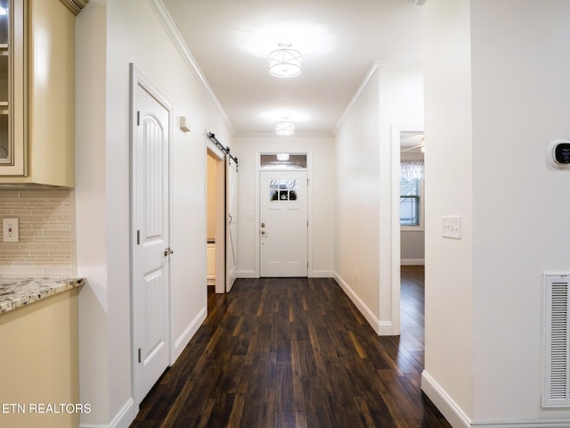 doorway to outside with crown molding, a barn door, and dark hardwood / wood-style floors