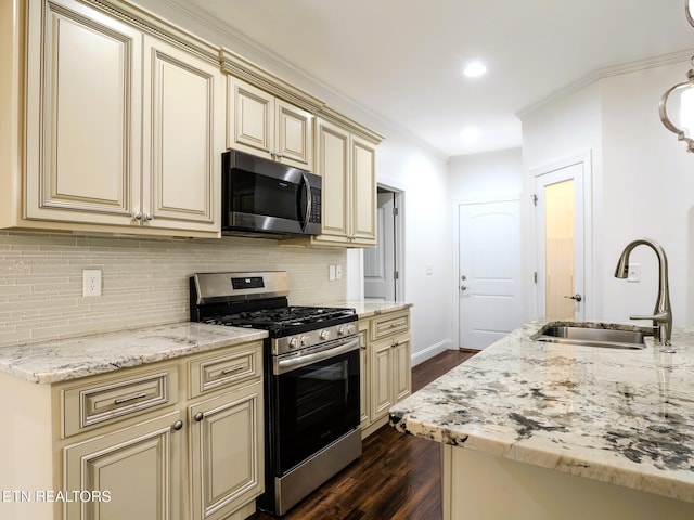 kitchen with tasteful backsplash, sink, light stone counters, stainless steel range with gas stovetop, and cream cabinetry