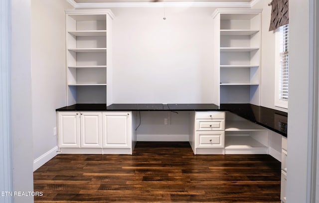 unfurnished office featuring dark hardwood / wood-style floors and built in desk