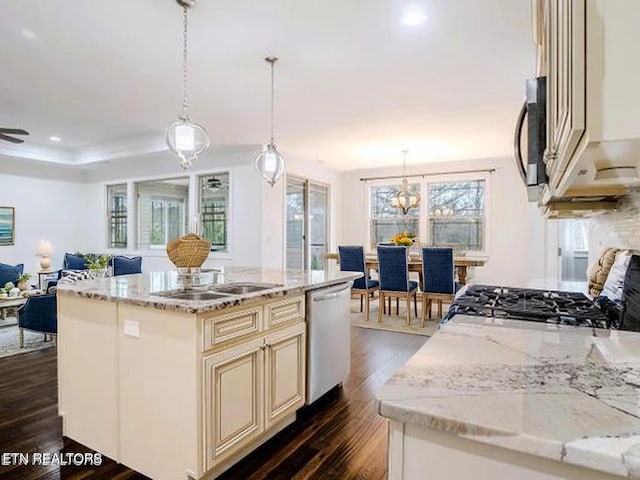 kitchen with appliances with stainless steel finishes, cream cabinets, open floor plan, dark wood-style floors, and light stone counters