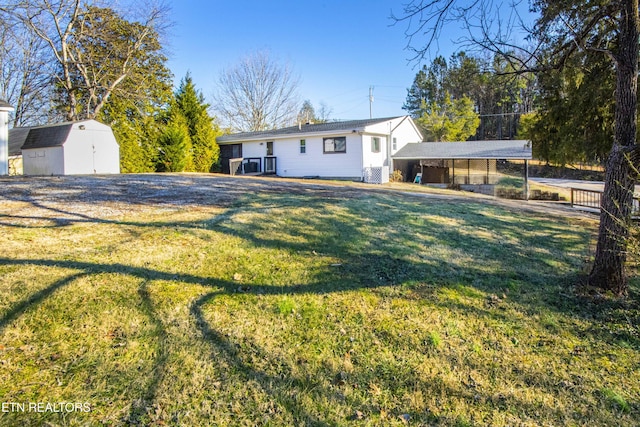 view of front of home featuring a storage shed, a front yard, and a carport