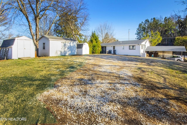 exterior space with cooling unit, a carport, and a storage unit