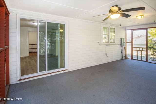 carpeted empty room with crown molding, ceiling fan, and wood walls