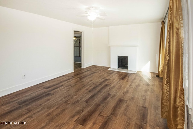 unfurnished living room featuring dark wood-type flooring and ceiling fan