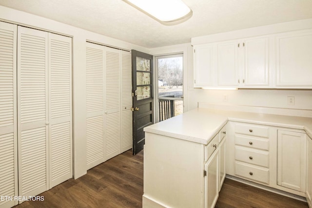 kitchen with dark wood-type flooring, kitchen peninsula, and white cabinets