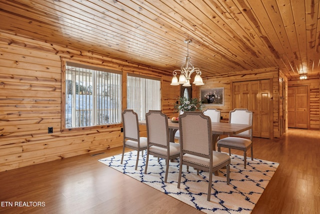 dining room featuring an inviting chandelier, hardwood / wood-style floors, wooden ceiling, and wood walls