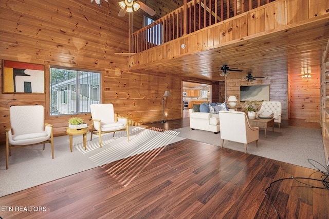 unfurnished living room featuring dark hardwood / wood-style flooring, wood walls, ceiling fan, and a high ceiling