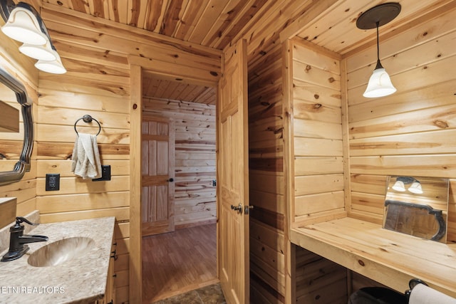 bathroom with wood ceiling, vanity, and wood walls