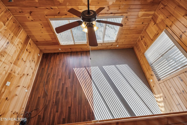 interior space with ceiling fan, carpet floors, wooden ceiling, and wooden walls