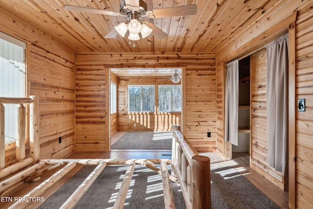 interior space with wood ceiling, wood walls, ceiling fan, and carpet flooring