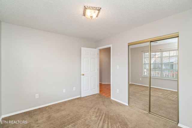 unfurnished bedroom with carpet floors, a textured ceiling, and a closet