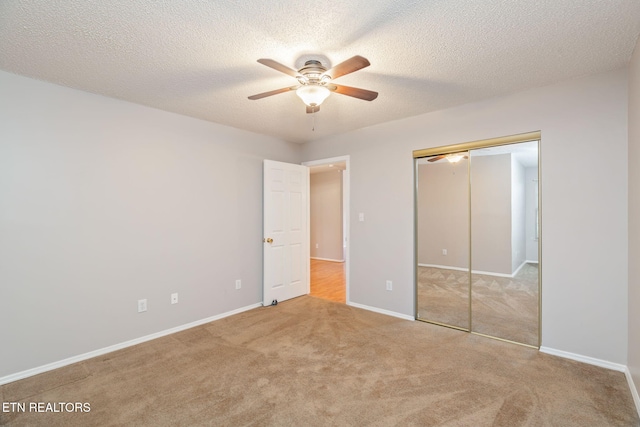 unfurnished bedroom featuring a textured ceiling, light colored carpet, a closet, and ceiling fan