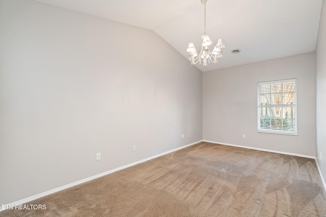 carpeted spare room with an inviting chandelier and vaulted ceiling