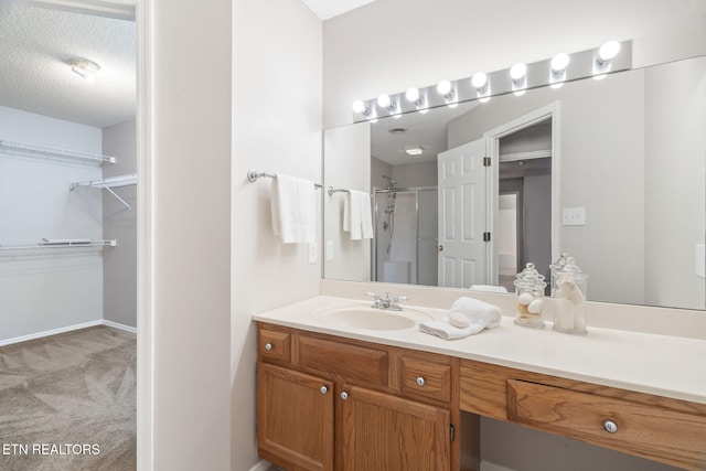 bathroom featuring vanity, a textured ceiling, and walk in shower