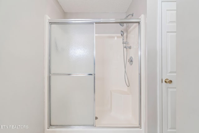 bathroom featuring an enclosed shower and a textured ceiling