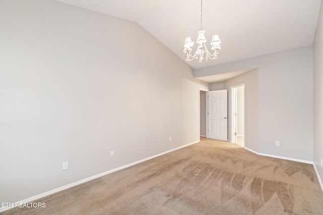 carpeted empty room featuring lofted ceiling and a chandelier