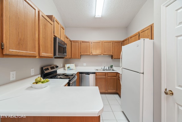 kitchen featuring sink, a textured ceiling, light tile patterned floors, kitchen peninsula, and stainless steel appliances