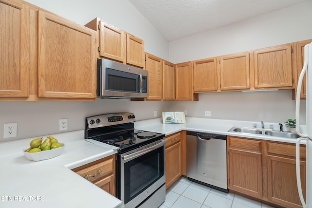 kitchen with sink, light tile patterned floors, a textured ceiling, and appliances with stainless steel finishes