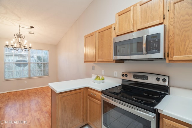 kitchen with lofted ceiling, decorative light fixtures, light hardwood / wood-style flooring, appliances with stainless steel finishes, and kitchen peninsula