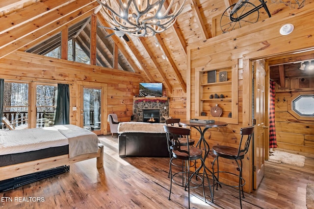 bedroom featuring hardwood / wood-style floors, wood ceiling, wooden walls, and high vaulted ceiling