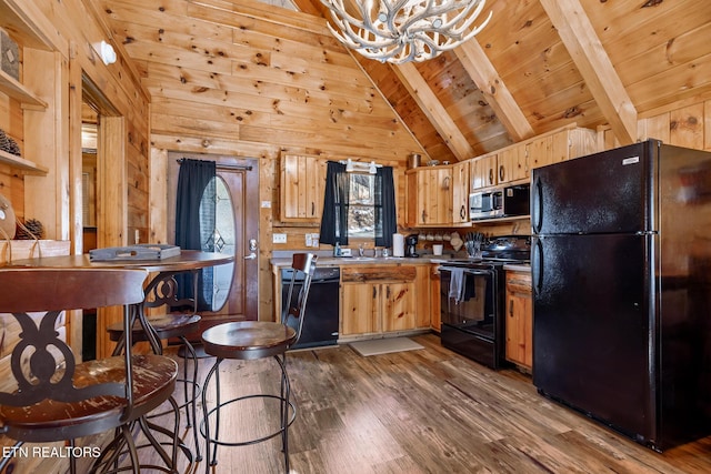 kitchen with wood walls, beamed ceiling, wood-type flooring, black appliances, and wooden ceiling