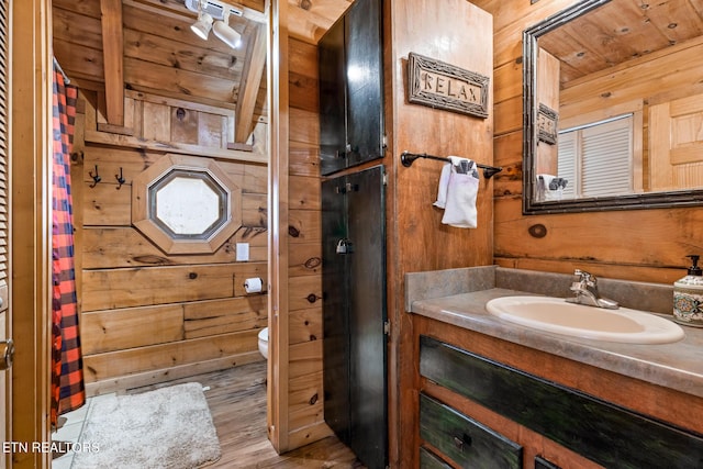 bathroom featuring beamed ceiling, vanity, wooden walls, and wooden ceiling