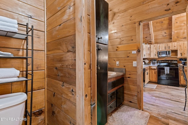 bathroom featuring toilet, hardwood / wood-style floors, and wood walls