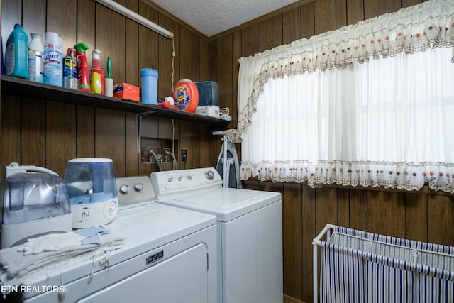 laundry area featuring washer and dryer, a textured ceiling, and wood walls