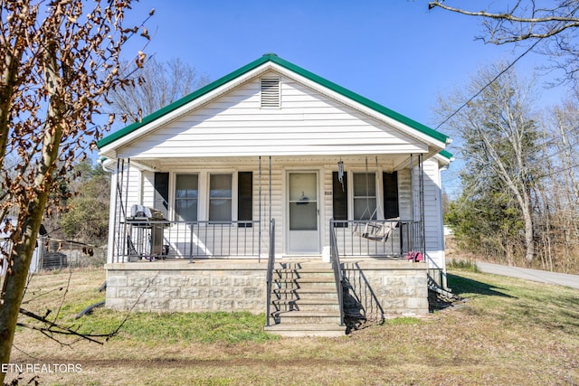 bungalow with covered porch and a front lawn