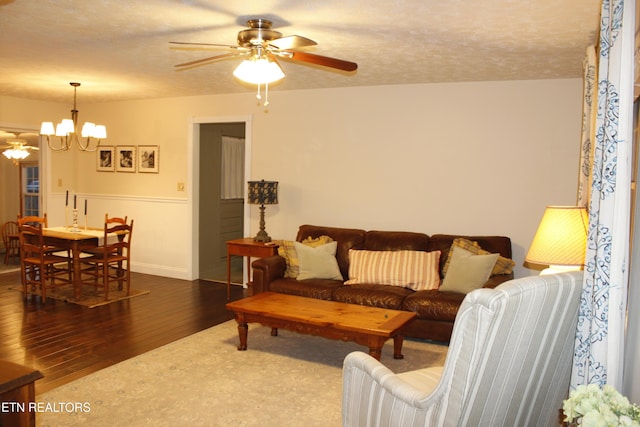 living room featuring ceiling fan with notable chandelier, dark hardwood / wood-style floors, and a textured ceiling