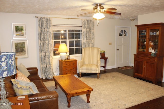 living room with ceiling fan, dark hardwood / wood-style floors, and a textured ceiling