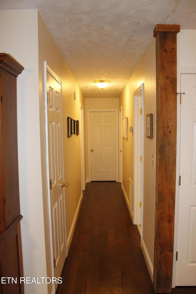 hall with dark hardwood / wood-style flooring and a textured ceiling