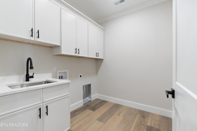 clothes washing area featuring cabinet space, hookup for an electric dryer, a sink, light wood-type flooring, and baseboards