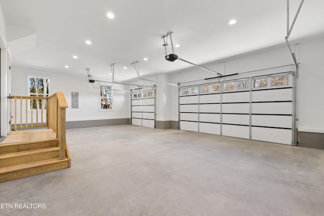 garage featuring a garage door opener, recessed lighting, and electric panel