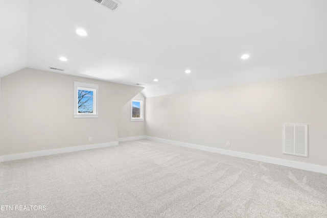 additional living space with lofted ceiling, baseboards, light carpet, and visible vents