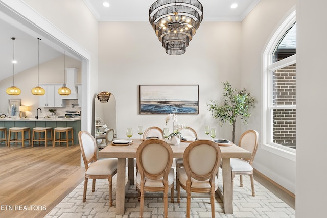 dining room with a chandelier, ornamental molding, light wood-type flooring, and baseboards