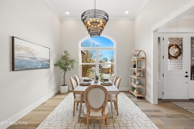 dining area with ornamental molding, light wood-style floors, a notable chandelier, and baseboards