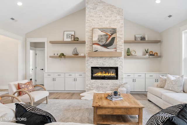 living room with light wood-type flooring, a fireplace, and vaulted ceiling